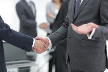 Business partners handshaking over business objects on workplace