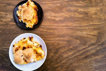 Portions of casserole, arranged in two round plates on the left side of the image, top view on a wooden background.