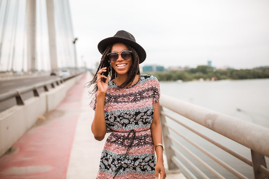 Smiled African American Woman Is Having Phone Call While Crossing Over A Bridge