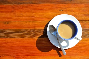 Coffee with milk on a wooden table on a sunny afternoon.