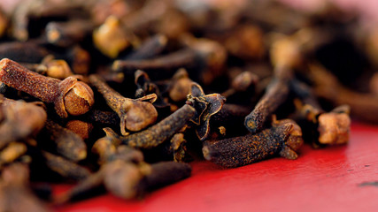 Cloves cooking spices macro closeup. on vintage red wood table, selective focus.