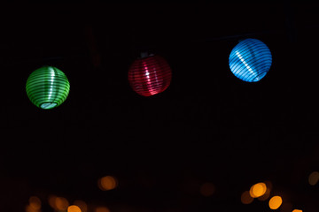 three green, red and blue lanterns at night with out of focus lights