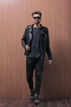a man is standing in a black leather jacket and jeans