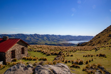 Hiking in New Zealand on Packhorse Track is the historic stone hut on the ridge overlooking the...