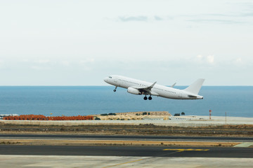 Fototapeta na wymiar departure of white jet airplane, runway and blue sea background