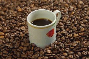 Taza de café rodeada de café tostado