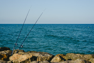 Fototapeta na wymiar Fishing rods fixed to the rocks near the sea coast without fishermen