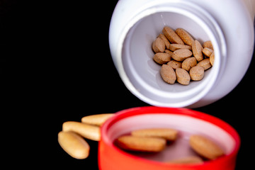oval brown tablets inside a white bottle on a dark blue background
