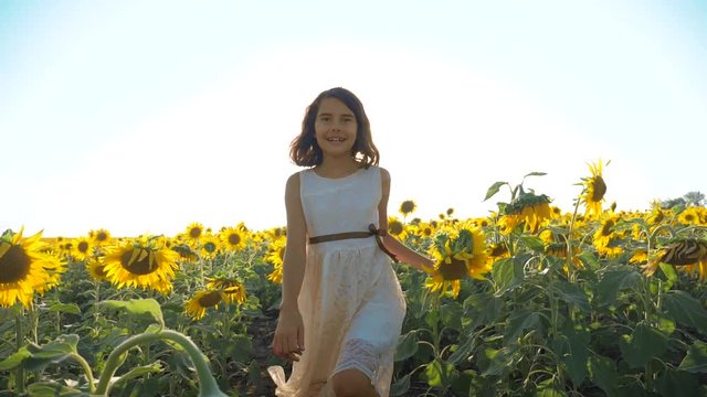 Happy little girl running happy free across the field with sunflowers. slow motion video. smelling big sunflower on summer field. Delight of a pleasant smell. Summer holiday. concept happiness