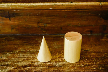 Solid wood shapes to study geometry and volumes, cones, triangles, squares, spheres on a warm wood...