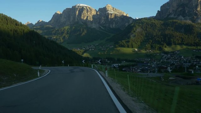 Driving just past dawn above Corvara, in Alta Badia, South Tyrol, Northern Italy. Dolomites peaks including Sassongher  tower over Corvara.
