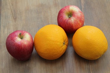 Apples and oranges on wood table.
