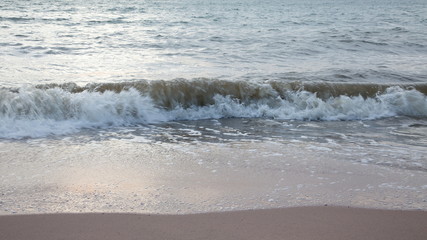 Sand beach with sea waves in the sunset.