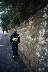 A woman wearing a yukata is walking down a path behind her