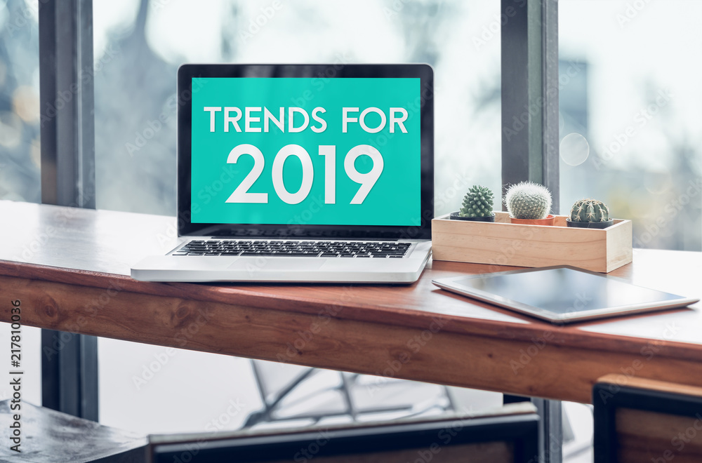 Aufkleber Trends for 2019 word in laptop computer screen with tablet on wood stood table in at window with blur background,Digital Business or marketing trending.