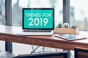 Trends for 2019 word in laptop computer screen with tablet on wood stood table in at window with blur background,Digital Business or marketing trending.