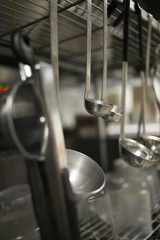 Ladles Hanging from a Stainless Steel Silver Metal Rack in an Industrial Kitchen
