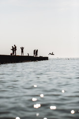 People rest on the pier. Silhouette photo. The man jumped into the water.