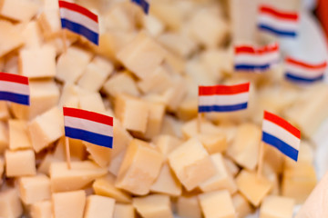 Fototapeta na wymiar Traditional Dutch snack cheese blocks on a plate and little Dutch paper flag as a cocktail pricker