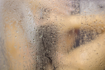 Beautiful woman in the shower behind glass with drops