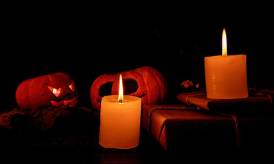 spooky halloween pumpkins with candles on wooden table with autumn leaves.two jack-o-lanterns