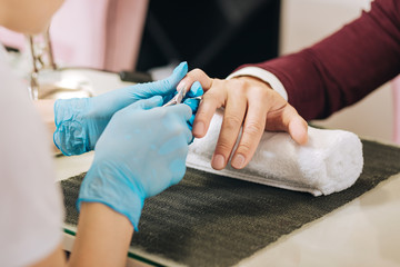 Nails for man. Close up of female hands dressing in gloves and having cuticle grip