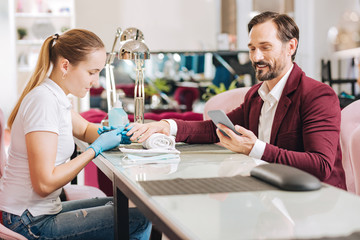 Professional style manicure. Woman giving manicure and happy mature man studying message