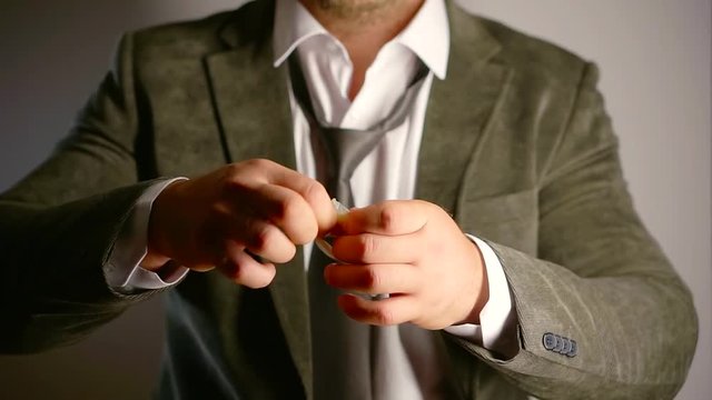 adult man is tying a used condom with sperm in a knot, demonstrating it in front of camera, close-up