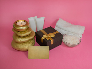 Gift set. Candle on stones, cosmetics, gift box and gift card. On a pink background.