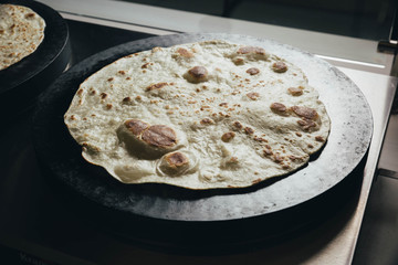 Tortilla on hot plate - thin, unleavened flatbread, typically made from corn or wheat. In Spanish, 