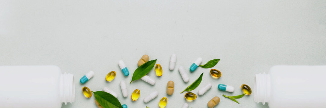 Different tablets, capsules, pills are scattered from the jar on a light background The concept of health Minimalism