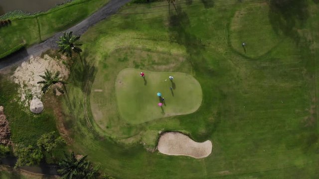 Golfer putting golf ball on the green golf - Aerial top view photo from flying drone