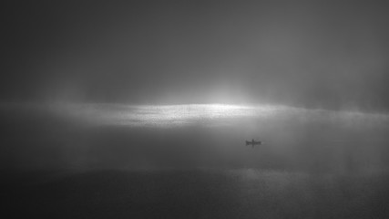 angler on a fog lake in the morning