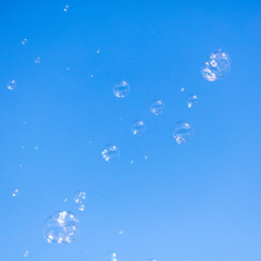 Soap bubbles in flight against the blue sky