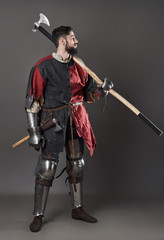 Medieval knight on grey background. Portrait of brutal dirty face warrior with chain mail armour...