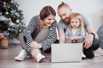 Young family of three using laptop while lying on carpet at home