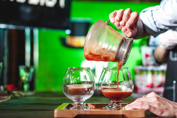 women's hands professionally barista pour the prepared drink into glass cups. championship among coffee houses, members of teams show barista's skill, prepare drinks, teamwork.