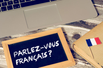 Ein Computer, Flagge von Frankreich und eine Kreidetafel mit der Frage Sprechen Sie französisch