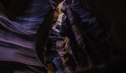 light reflects red, blue, and orange colors off the sandstone walls of slot canyon - Powered by Adobe