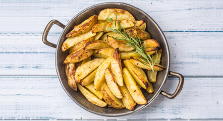 Roasted potatoes in a frying pan on wooden board