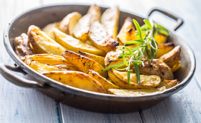 Roasted potatoes in a frying pan on wooden board