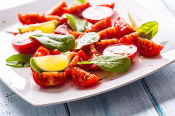Tasty tomatoes salad with lime spinach leaves and balsamic sauce