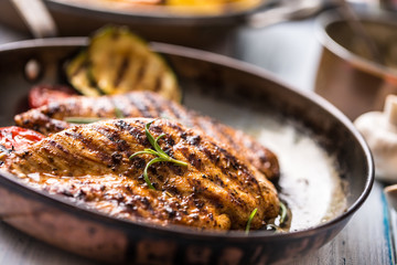 Grilled chicken breast in old frying pan.