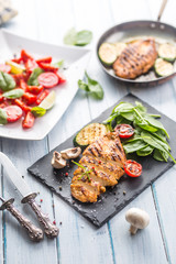 Grilled chicken breast on slate board.