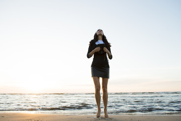 Fototapeta na wymiar The woman in black prays on the sea beach, meditation