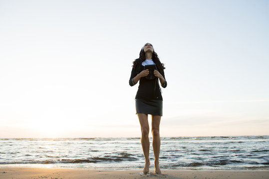 The woman in black prays on the sea beach, meditation