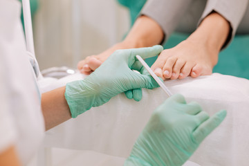 File and pedicure. Professional chiropodist wearing bright gloves using file while making pedicure for woman © Viacheslav Yakobchuk