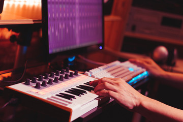 musician hands playing midi keyboard synthesizer for recording music on computer in digital sound...