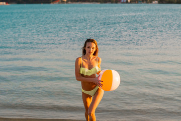 adorable slim lady in swimsuit with beach ball in the sea