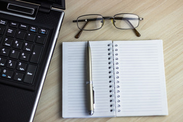 Office workplace with text space, White wooden table with office supplies tablet, desktop computer and book, top view, over light